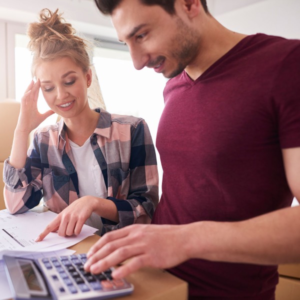 A couple evaluating their costs with a calculator with moving boxes around them