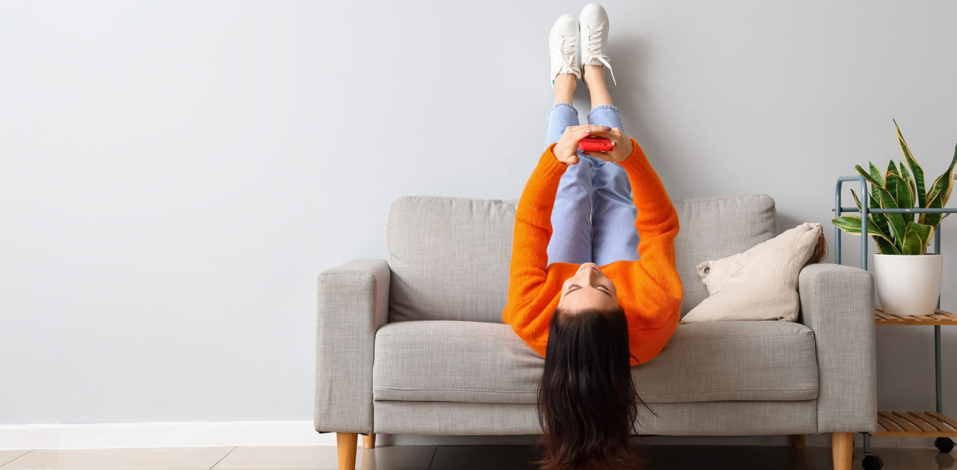 A person lying on a sofa making a phone call